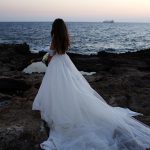 Bride's long dress by the water on the rocks